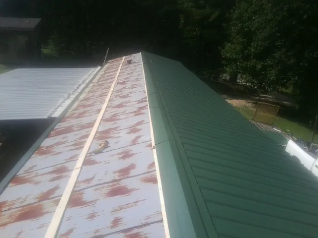 Old rusted panels beside newly installed green metal roofing — Wind Damage Roof Repair by Roofing Brothers in Staten Island