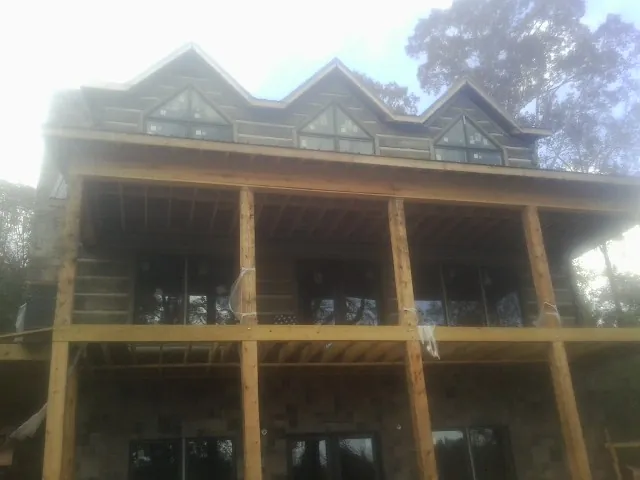 Dormers and porch framing on a large log home under construction — Roof Coating work by our crew in Staten Island