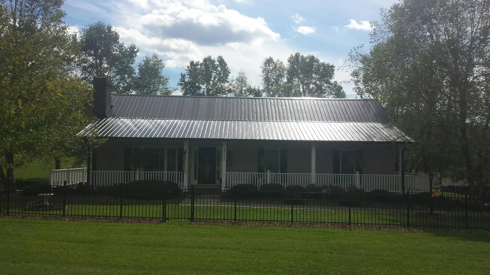 Gray metal roof on a brick ranch with a full width front porch — Gutter Guard Installation work by our crew in Staten Island