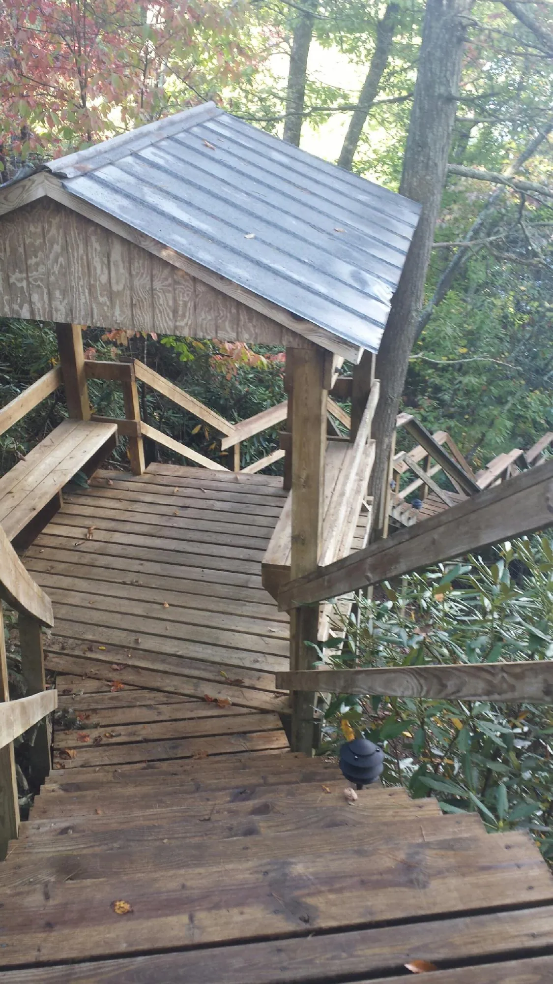 Metal roofed shelter over wooden steps on a wooded walkway — Skylight Repair & Installation work by our crew in Staten Island