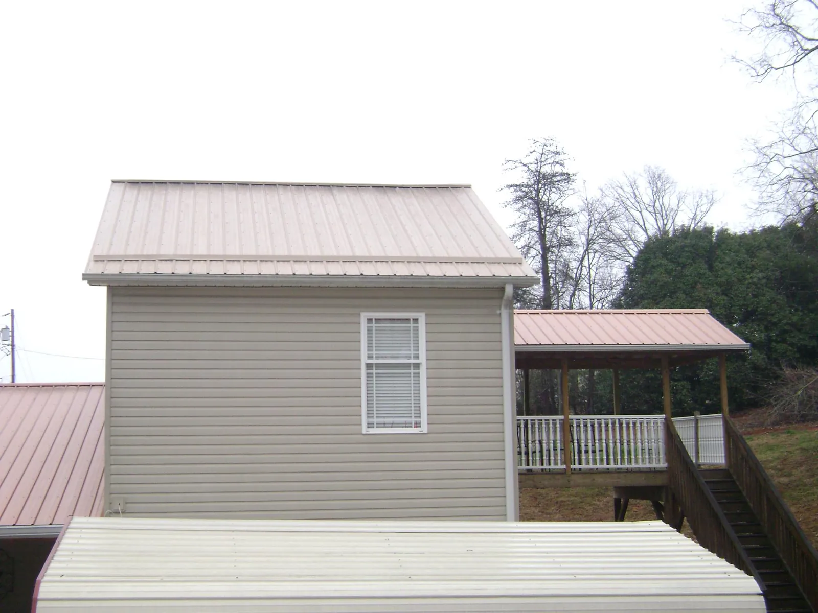 Tan metal roofs on a two story addition and attached porch, from a Roof Replacement job in Staten Island