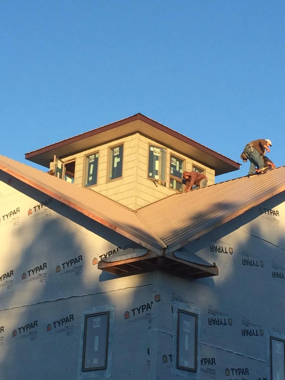 Roofers working around a rooftop cupola on a new metal roof at sunset — Roof Waterproofing in Staten Island by Roofing Brothers